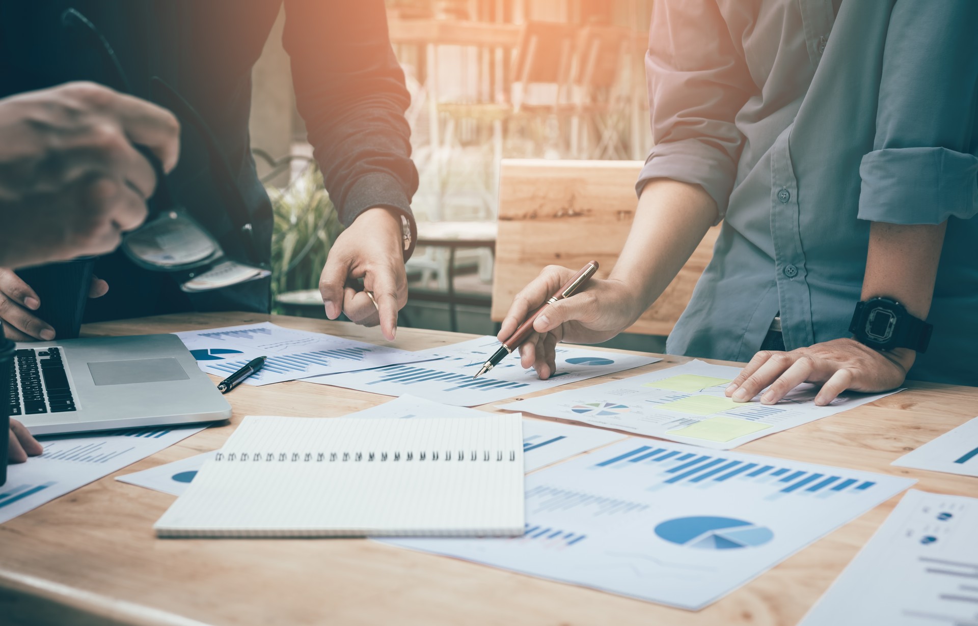 Co-working space office with group start-up analysis to data paper chart on desk.